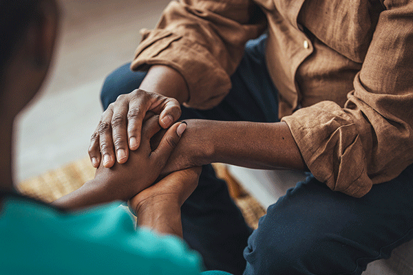 Two pairs of human hands are intertwined in a show of emotional support.